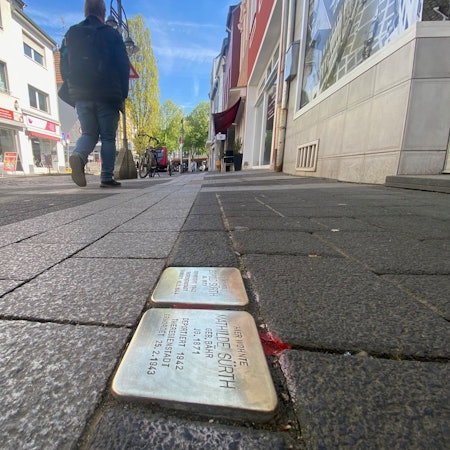 Zu sehen sind zwei Stolpersteine, die in einem Gehwegpflaster eingelassen sind.