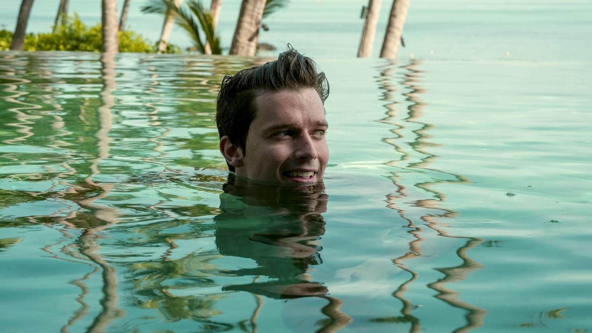 Patrick Schwarzenegger schwimmt in einem Pool, nur sein Kopf schaut aus dem Wasser.
