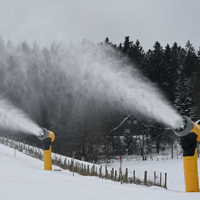 Schneekanonen stehen neben der Ski-Piste.