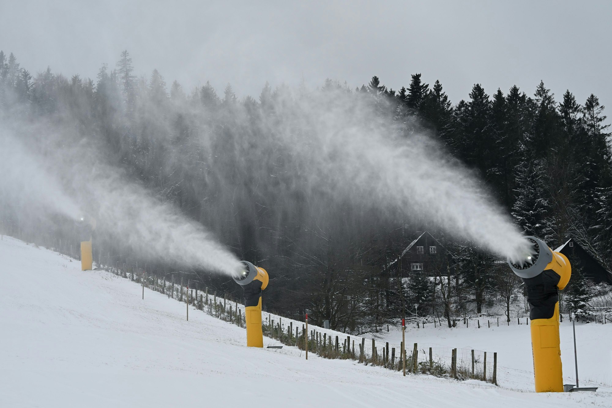 Schneekanonen stehen neben der Ski-Piste.