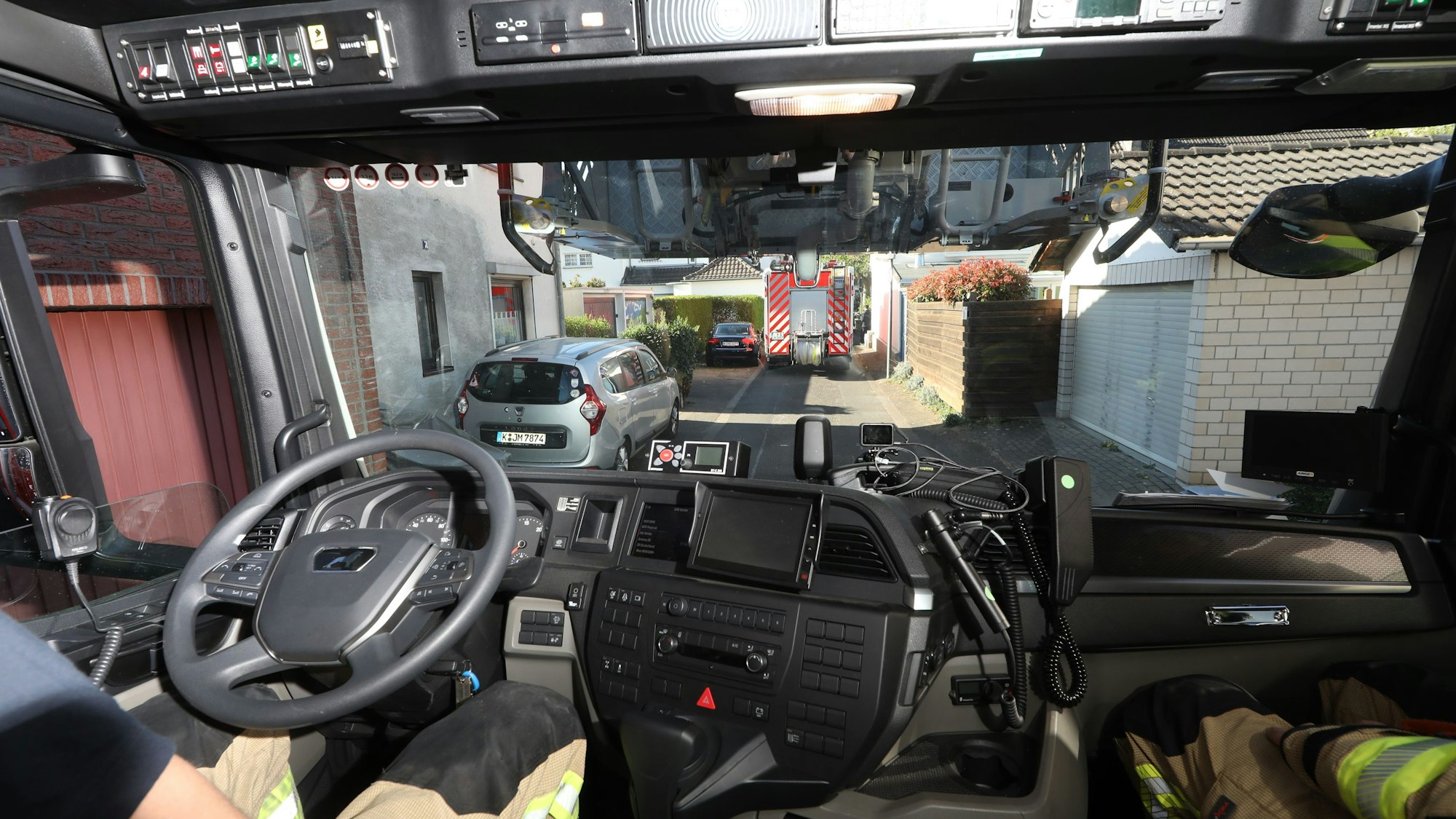Zu sehen ist die Innenansicht eines Feuerwehrwagens, der durch eine enge Straße fährt.