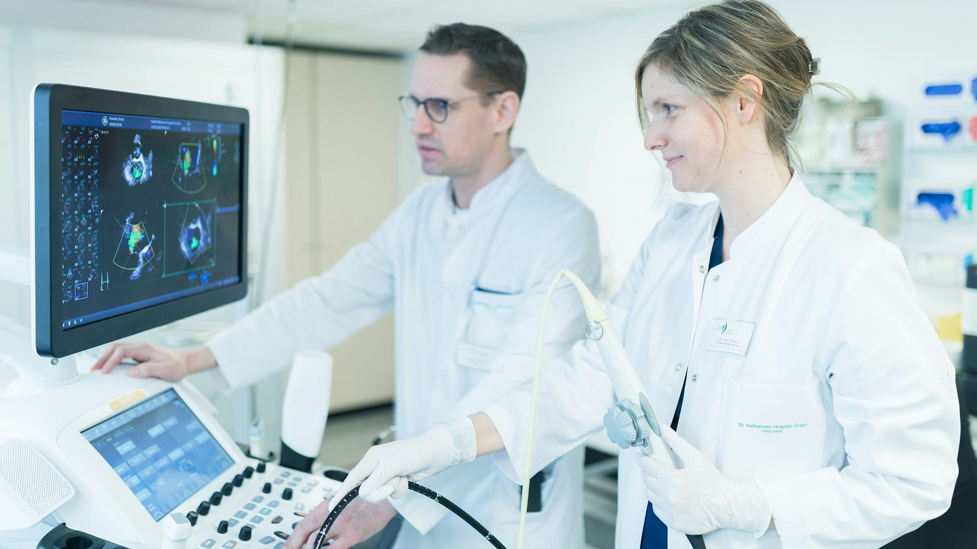 Auf dem Bild sind eine Ärztin und ein Arzt zu sehen, die gemeinsam an einem medizinischen Gerät arbeiten.