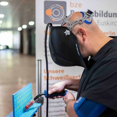Ein Mann übt mithilfe eines Simulators das Schweißen. Funken sprühen dabei nur am Monitor.