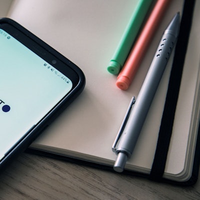 Ein Handy mit offenem ChatGPT-Programm liegt auf einem Schreibtisch.