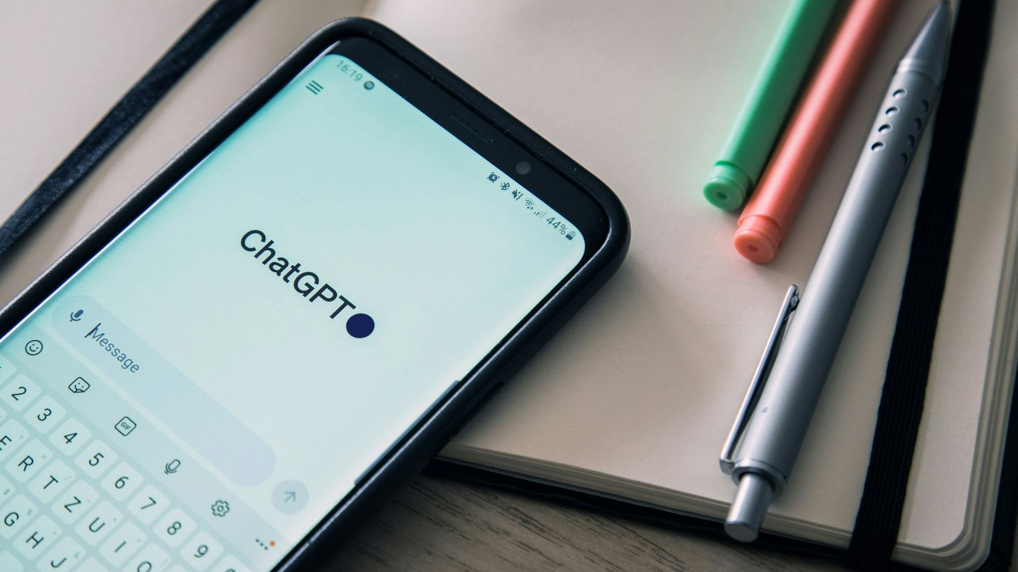 Ein Handy mit offenem ChatGPT-Programm liegt auf einem Schreibtisch.