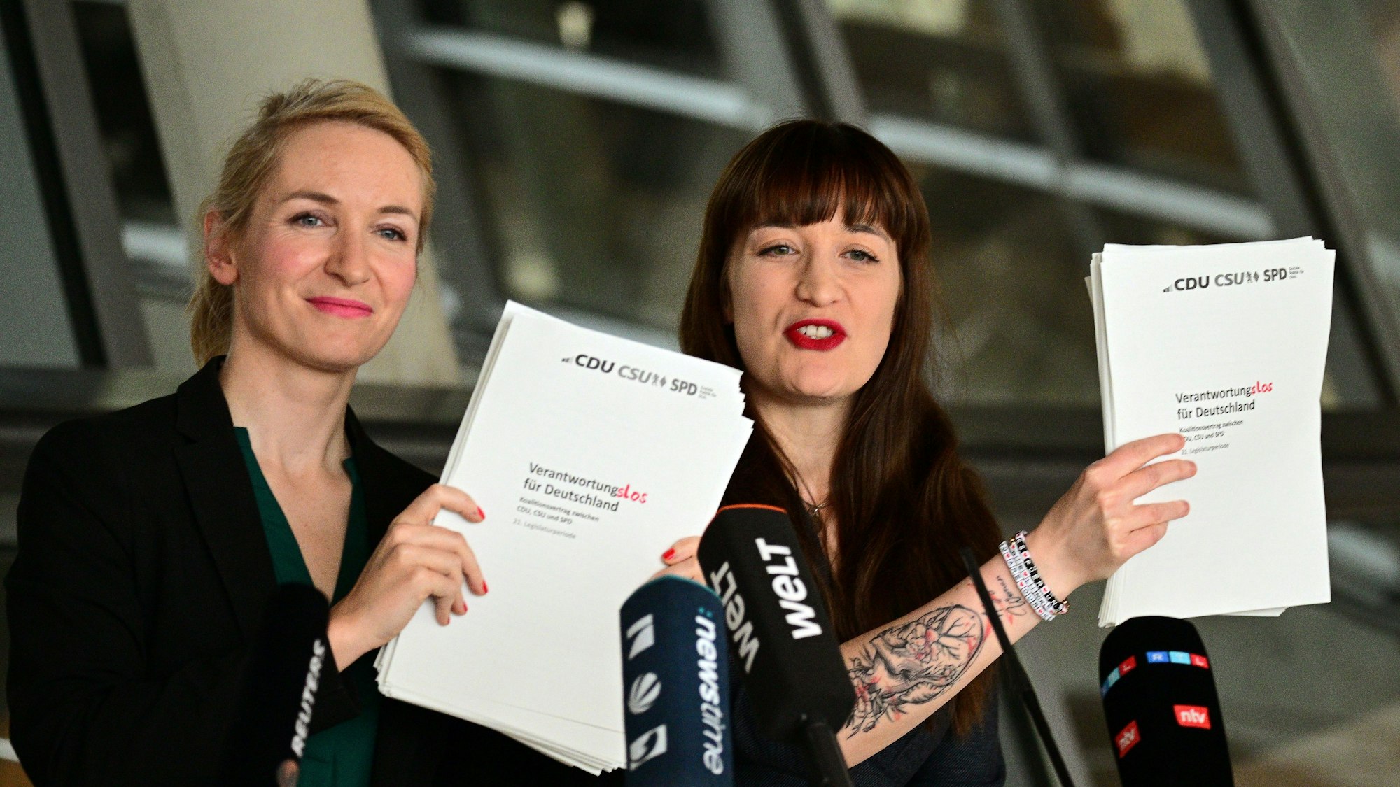 Ines Schwerdtner und Heidi Reichinnek halten Kopien des Koalitionsvertrages mit dem veränderten Schriftzug „Verantwortungslos für Deutschland“ hoch.