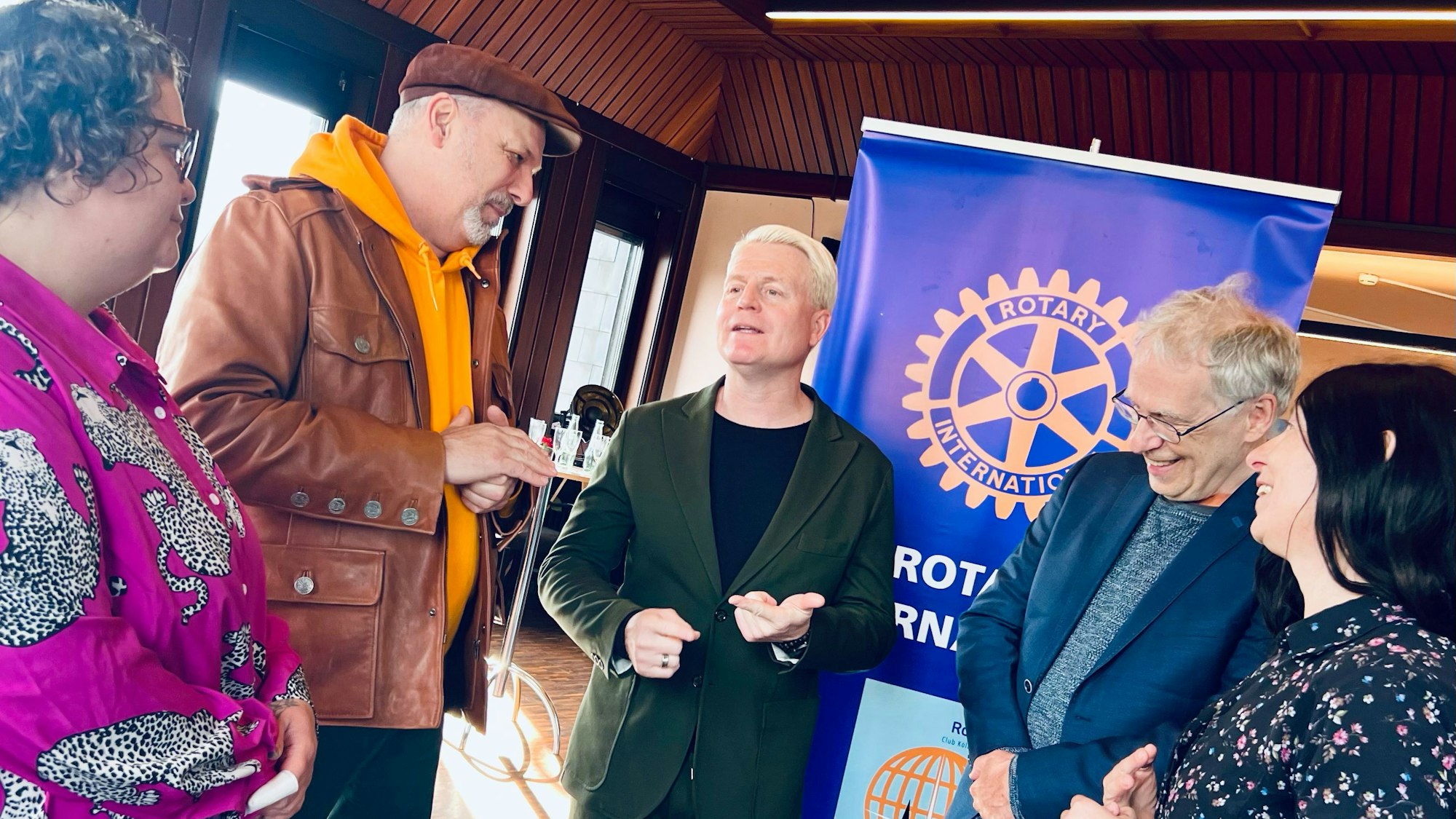 Zwei Frauen und drei Männer stehen vor einem Roll-Up-Banner, auf dem Rotary International steht.
