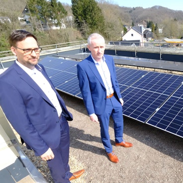 Kai Zinken (r.) und Abteilungsleiter Jörg Schröder stehen auf dem Dach neben PV-Modulen.