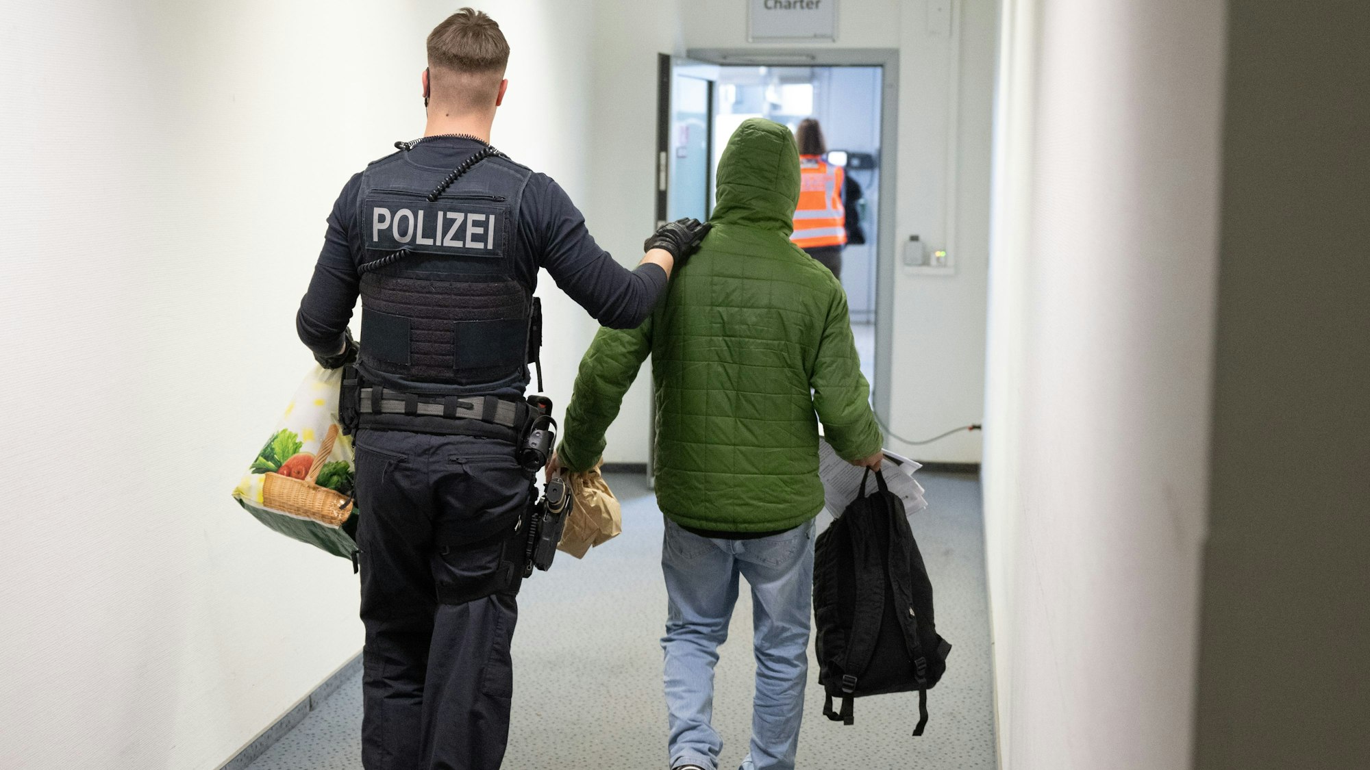 Ein Polizeibeamter bringt einen Mann zu einem Abschiebeflug.