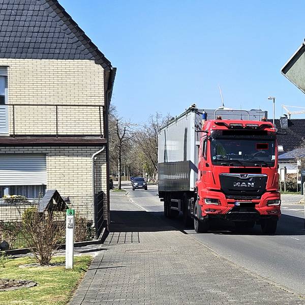 Ein Lastwagen mit Auflieger fährt nahe an Häusern in Schöneseiffen vorbei.