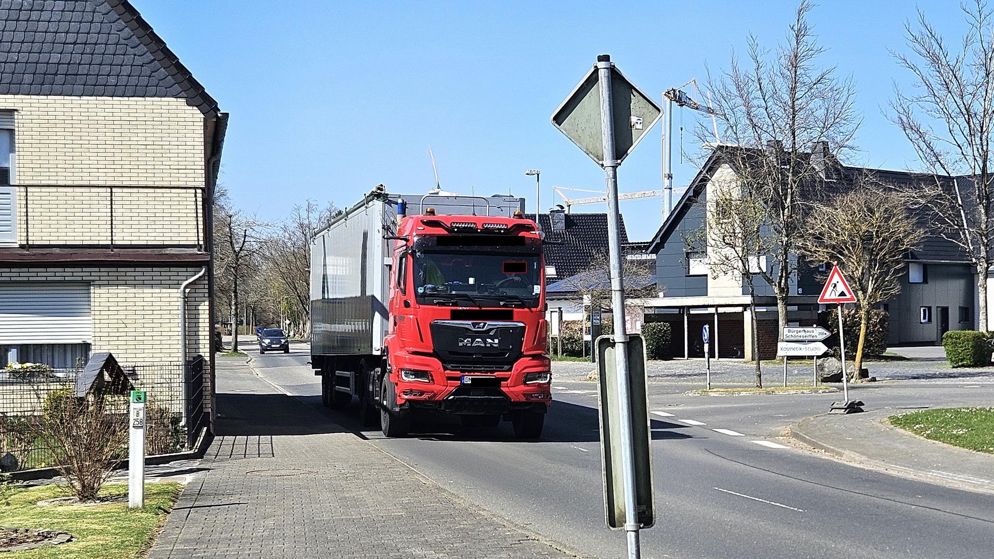 Ein Lastwagen mit Auflieger fährt nahe an Häusern in Schöneseiffen vorbei.