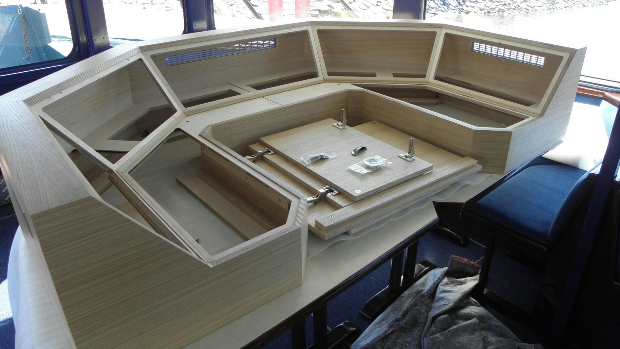 Ein Holzgestell liegt auf zwei Tischen. Daraus wird die Kommandobrücke eines Schiffes auf dem Rursee. In die Aussparungen werden digitale Kontrollbildschirme eingesetzt.