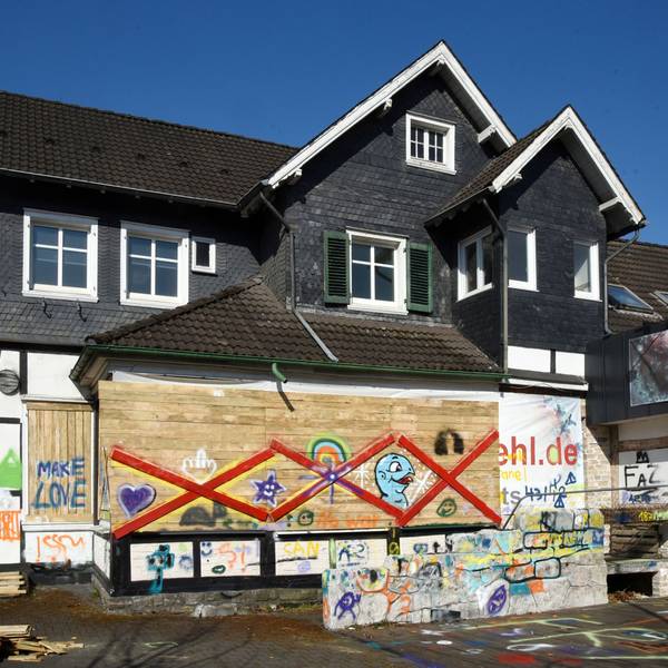 Ein altes Haus mit Bretterverschlägen, die bunt besprüht wurden.