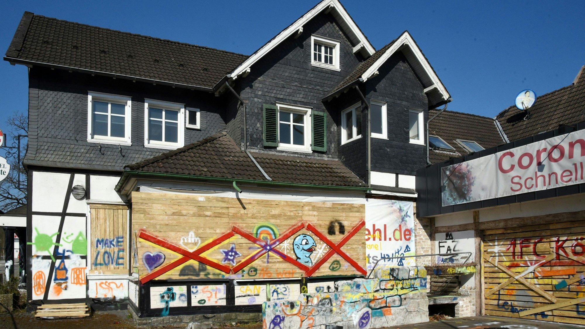 Ein altes Haus mit Bretterverschlägen, die bunt besprüht wurden.
