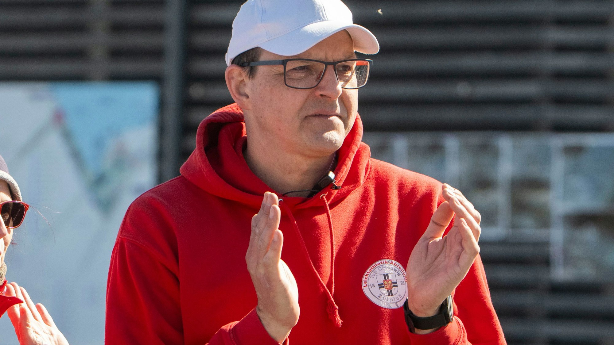 Markus Mollek vom TuS Zülpich trägt einen roten Pullover und eine weiße Kappe. Er applaudiert.