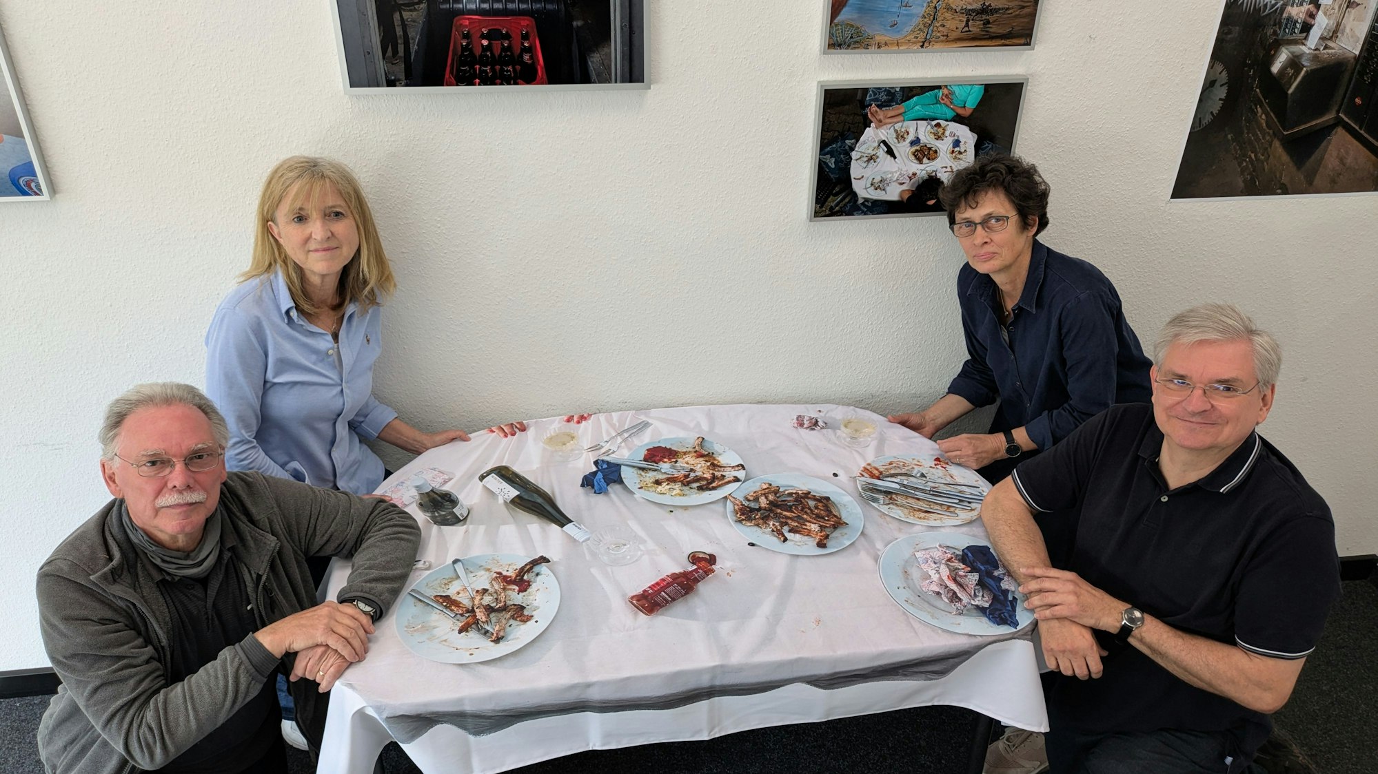 Zwei Männer und zwei Frauen sitzen in einer Ausstellung an einem Tisch.