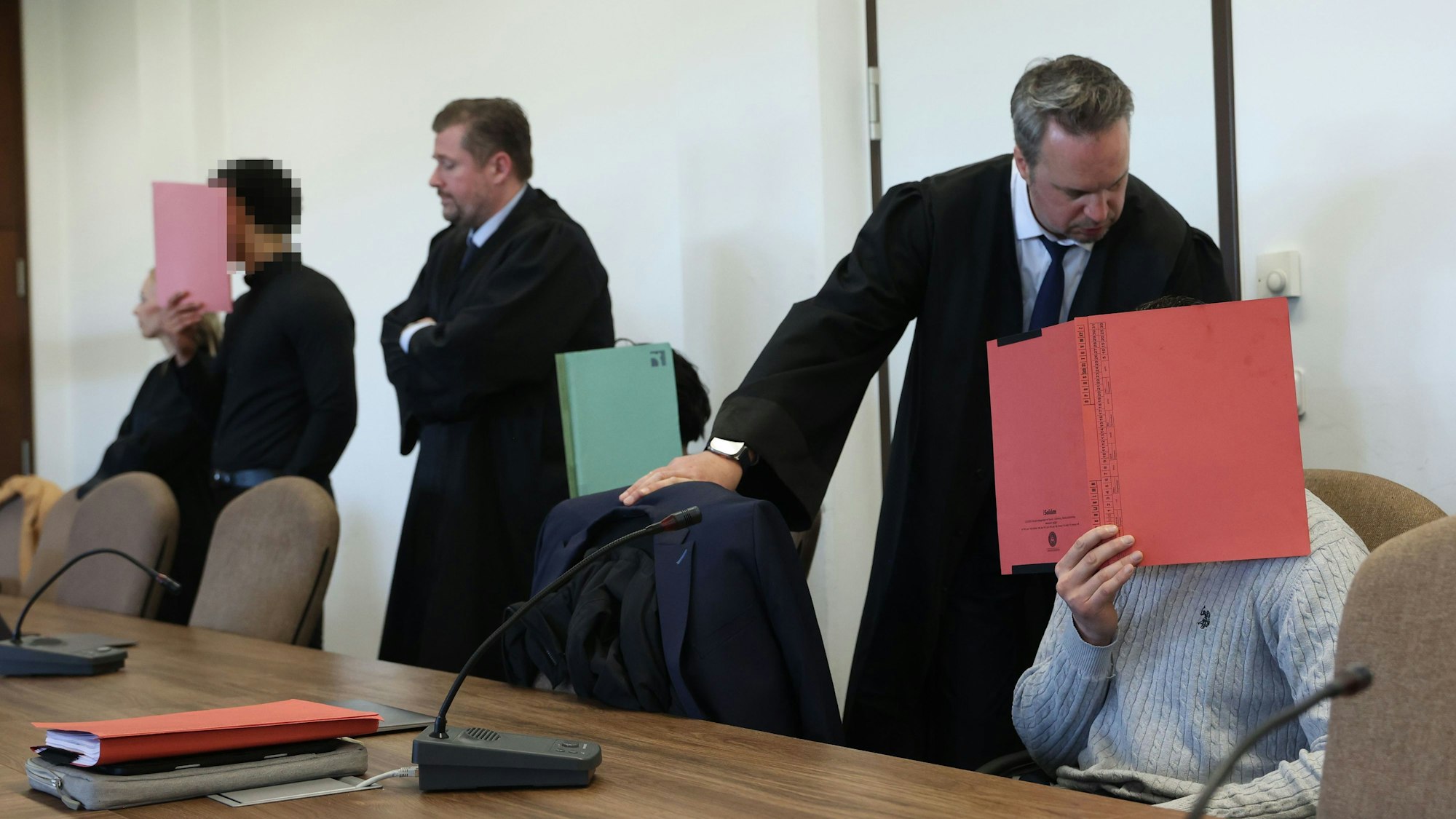 Die drei Angeklagten mit ihren Verteidigern beim Prozessauftakt im Kölner Landgericht