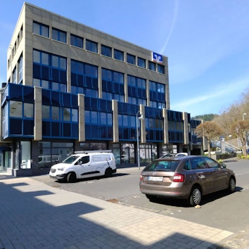 Das Verwaltungsgebäude der VR-Bank Nordeifel in Schleiden. Davor parken einige Autos.