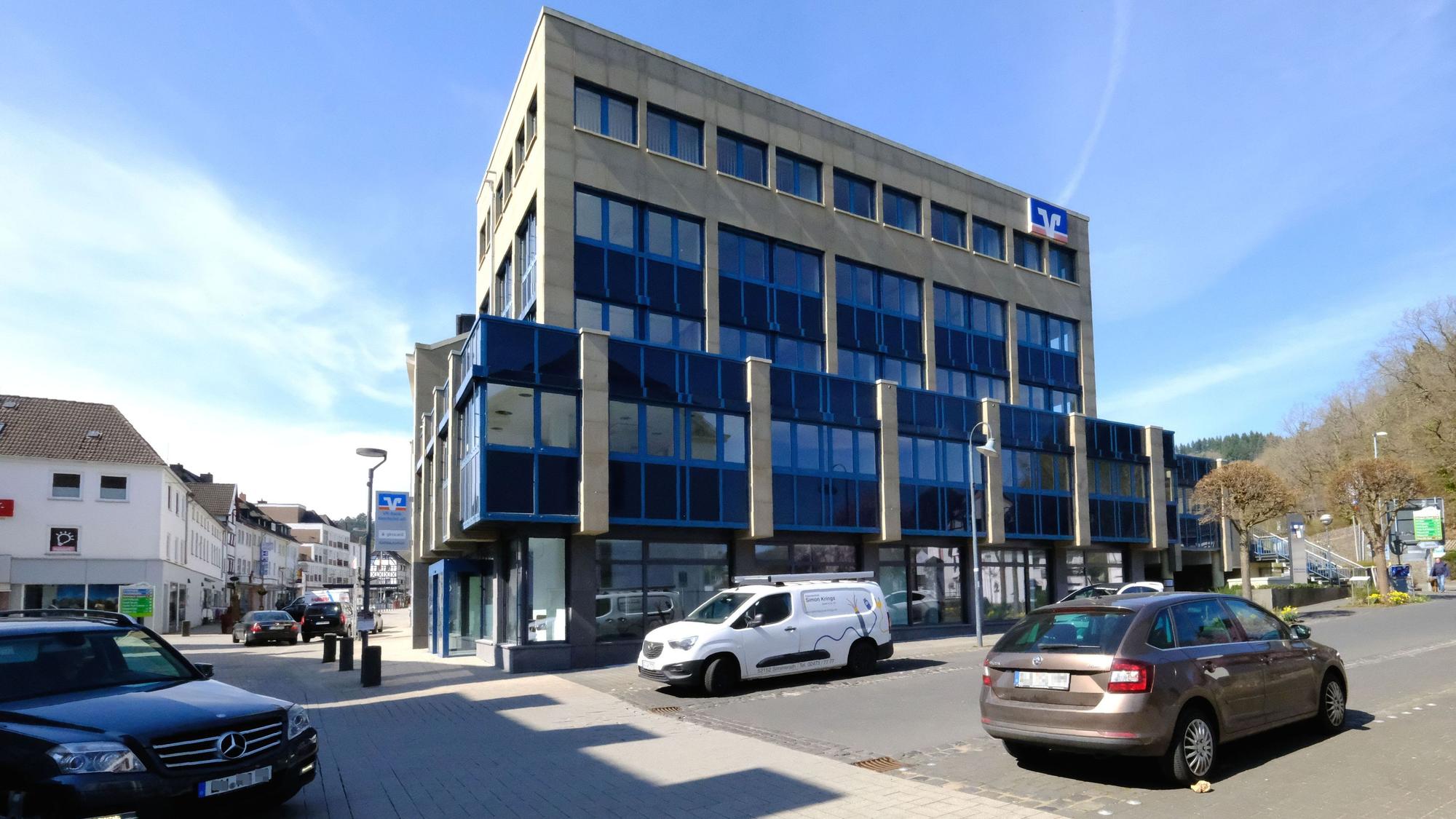 Das Verwaltungsgebäude der VR-Bank Nordeifel in Schleiden. Davor parken einige Autos.