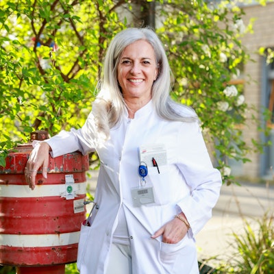 Eine Ärztin steht mit einem weißen Kittel neben einem Hydranten.