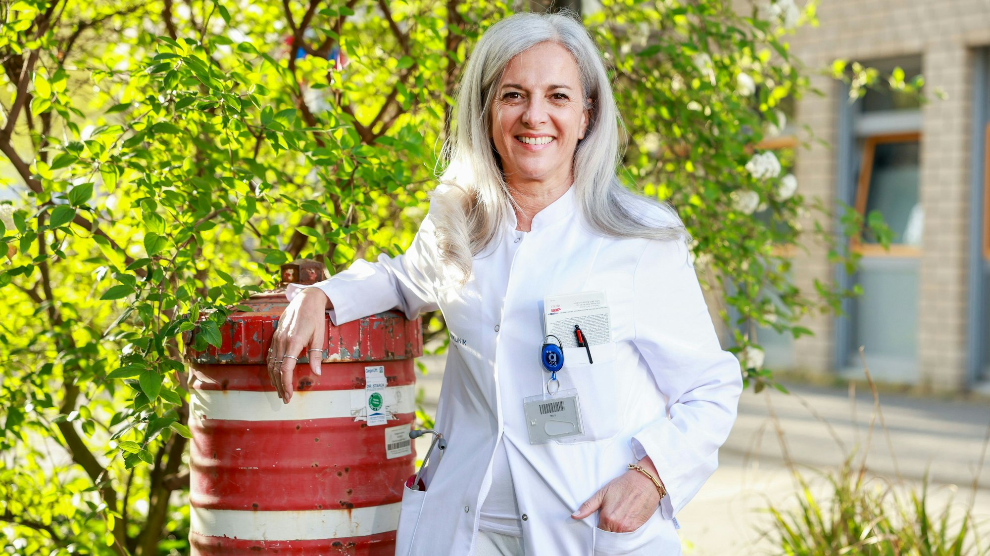 Eine Ärztin steht mit einem weißen Kittel neben einem Hydranten.