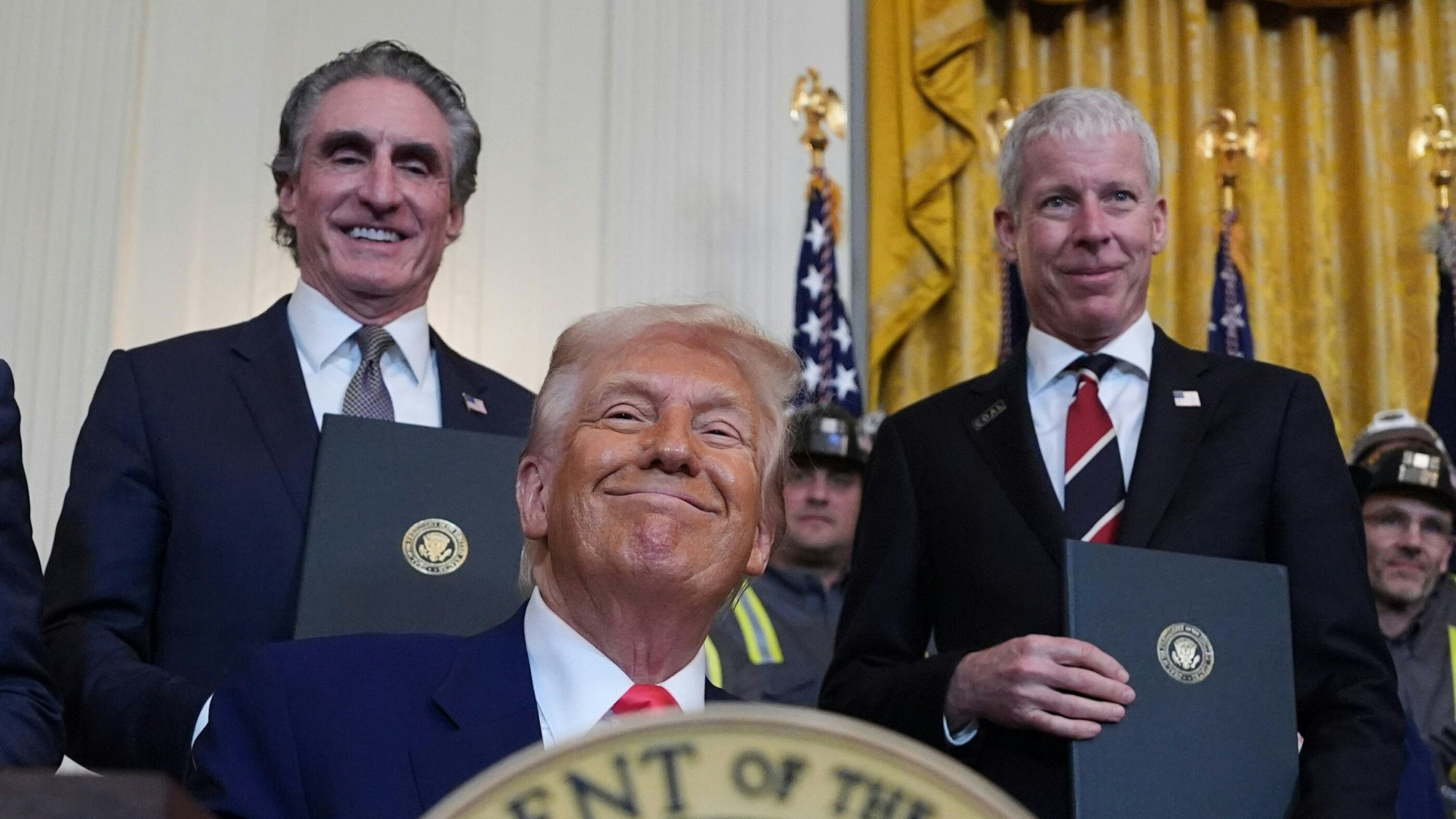 Das Bild zeigt US-Präsident Donald Trump (mitte) mit Innenminister Doug Burgum (links) und Energieminister Chris Wright (rechts) zusehen.