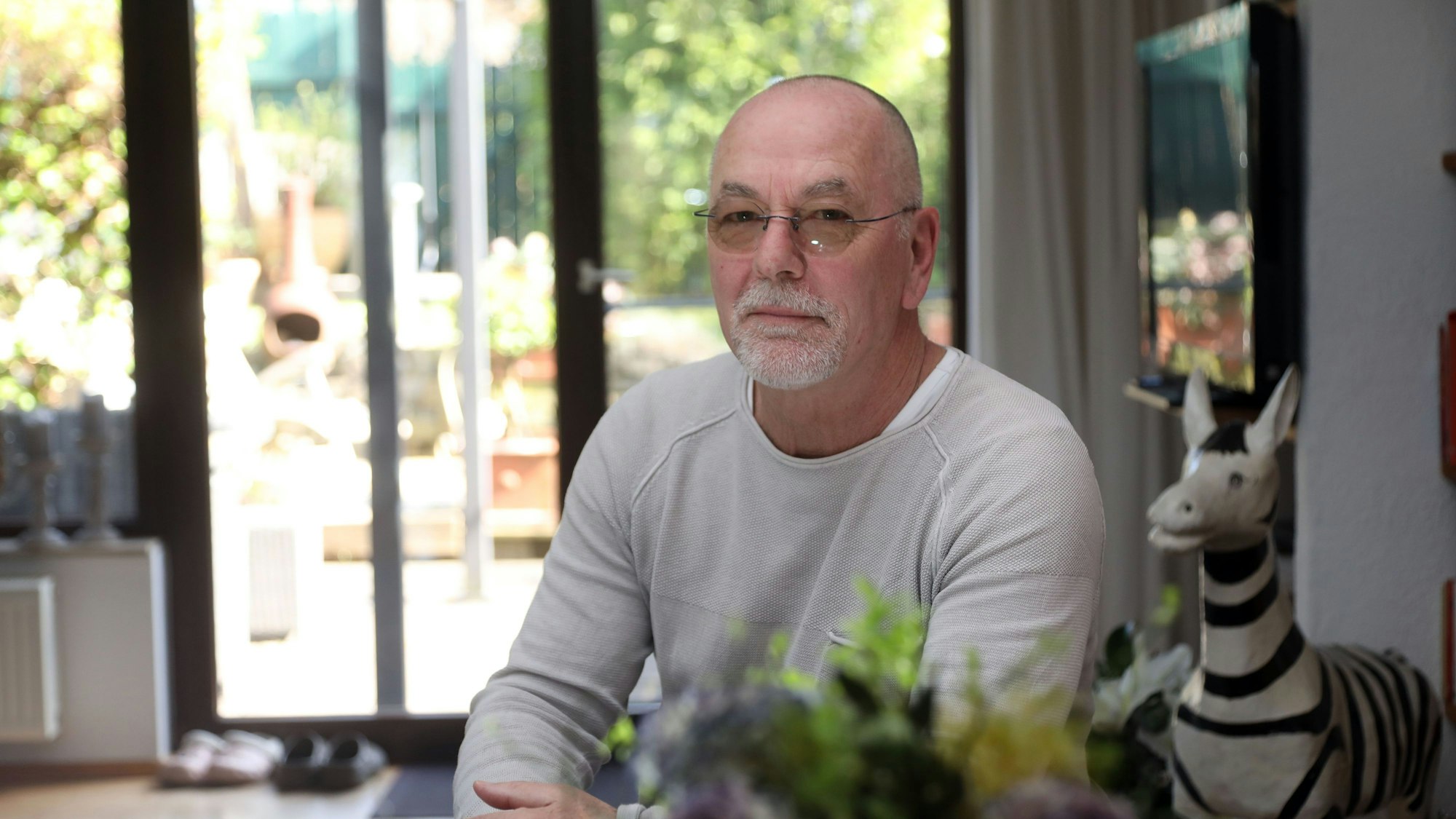 Polizist Hartmut Berg sitzt im Inneren einen Hauses.