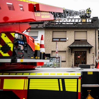 Das Bild zeigt den ausgebrannten Dachstuhl und die Drehleiter der Weilerswister Feuerwehr. Ein Feuerwehrmann schaut nach Glutnestern.