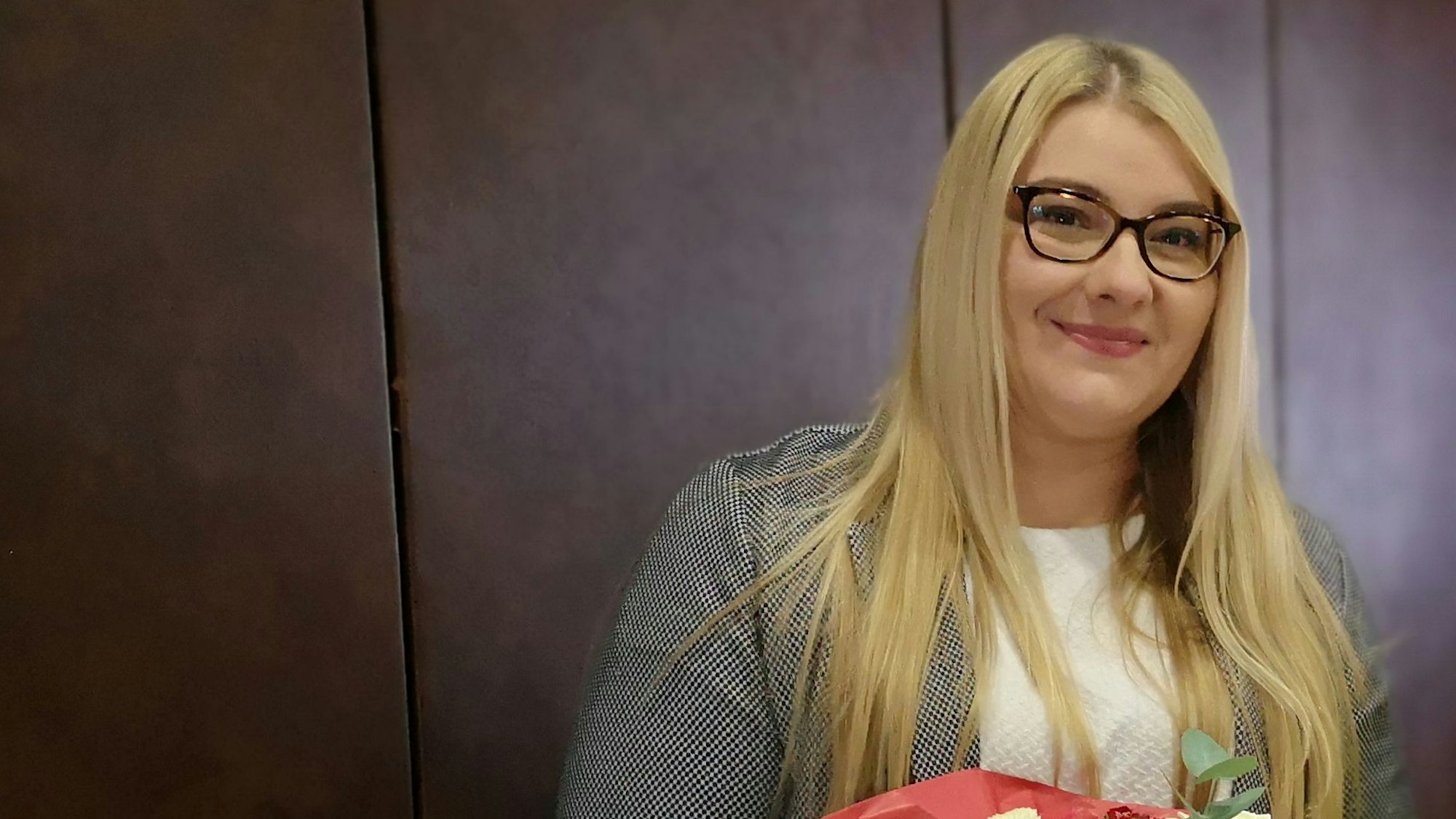 Auf dem Foto ist eine Frau mit langem blonden Haar und einer Brille zu sehen.