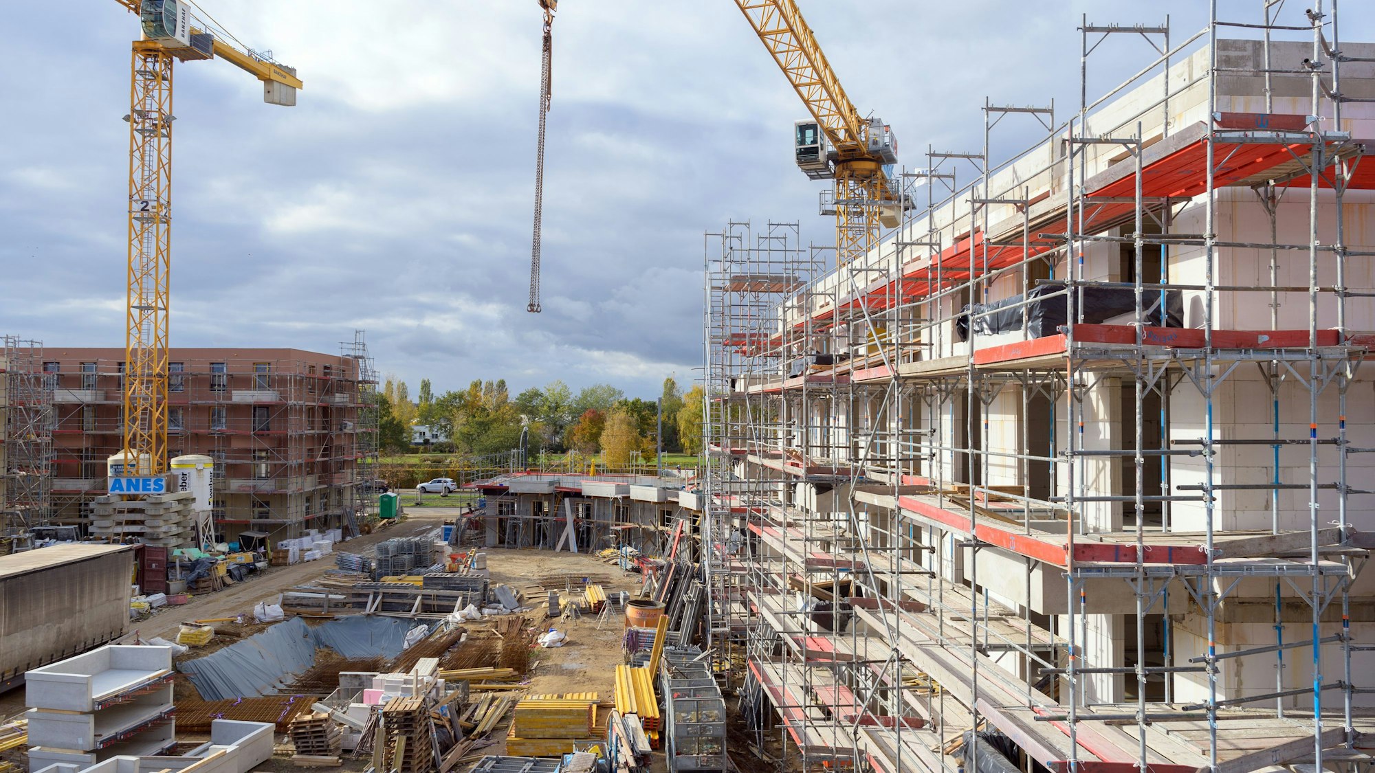 Gerüste stehen auf einer Baustelle an Rohbauten von Häusern. (Symbolbild)