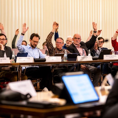 Das Bild zeigt einen Moment der Kreistagssitzung. Einige Politiker heben während der Abstimmung ihren Arm.
