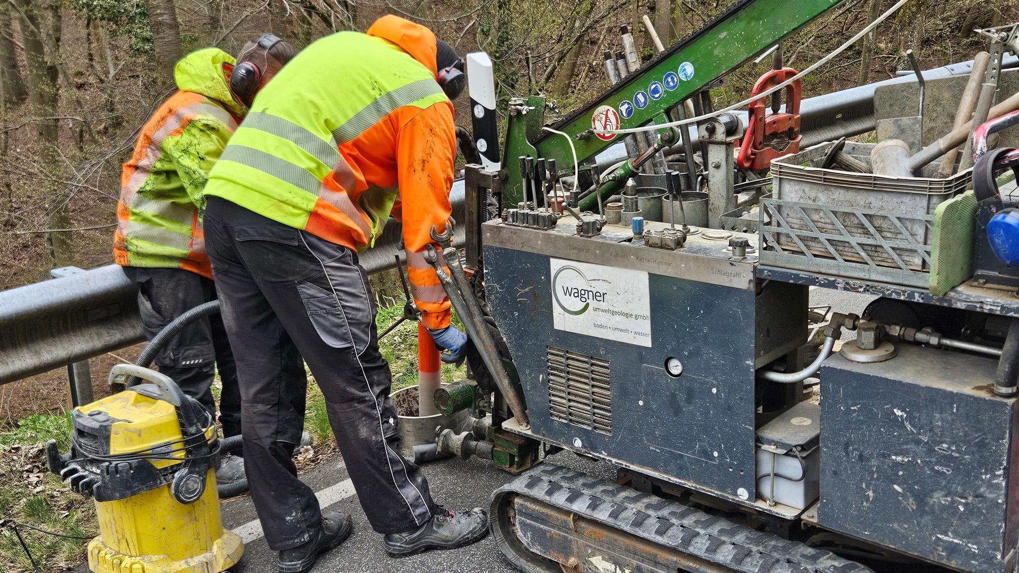 Zwei Mitarbeiter bedienen eine mobile Bohrmaschine für Straßen.