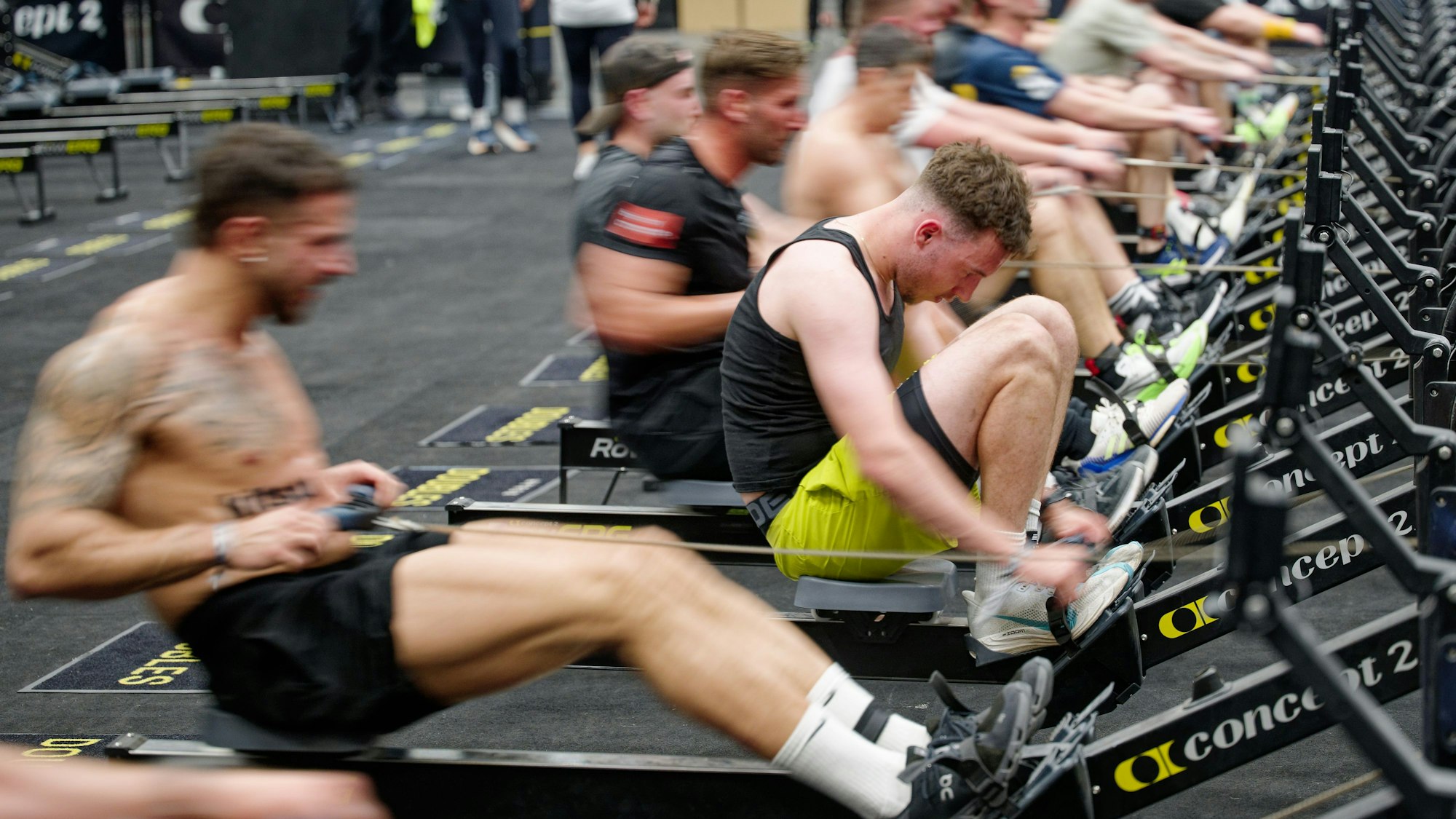 10.04.2025, Nordrhein-Westfalen, Köln: Teilnehmer rudern bei einem HYDROX-Wettbewerb an Rudermaschinen auf der Fitnessmesse "Fibo 2025". HYROX gehört zur Indoor-Fitness und kombiniert acht Kilometer Laufen mit acht Functional-Workout-Stationen. Die Messe präsentiert Fachbesuchern und Verbrauchern neue Trends rund um Fitness, Wellness und Gesundheit. Foto: Henning Kaiser/dpa +++ dpa-Bildfunk +++