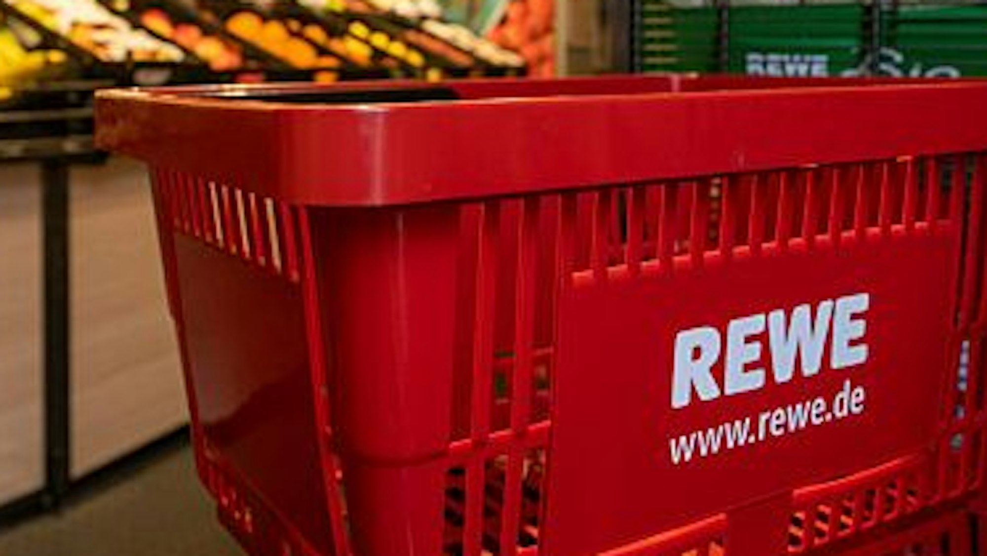 Das Logo der Supermarktkette Rewe ist auf einem Einkaufskorb zu sehen,