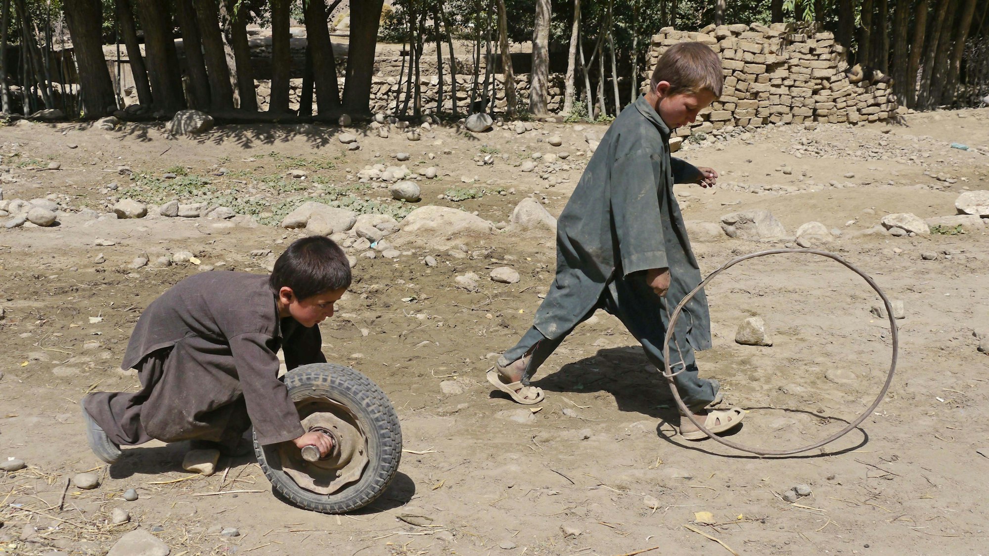 Zwei Jungs spielen mit einem Reifen und einem Rad.