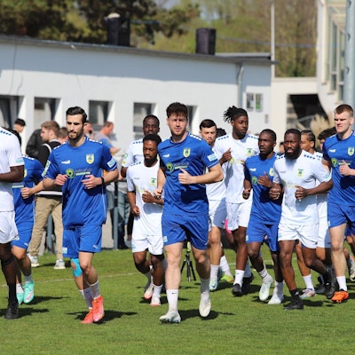 Fußballer joggen über einen Platz.