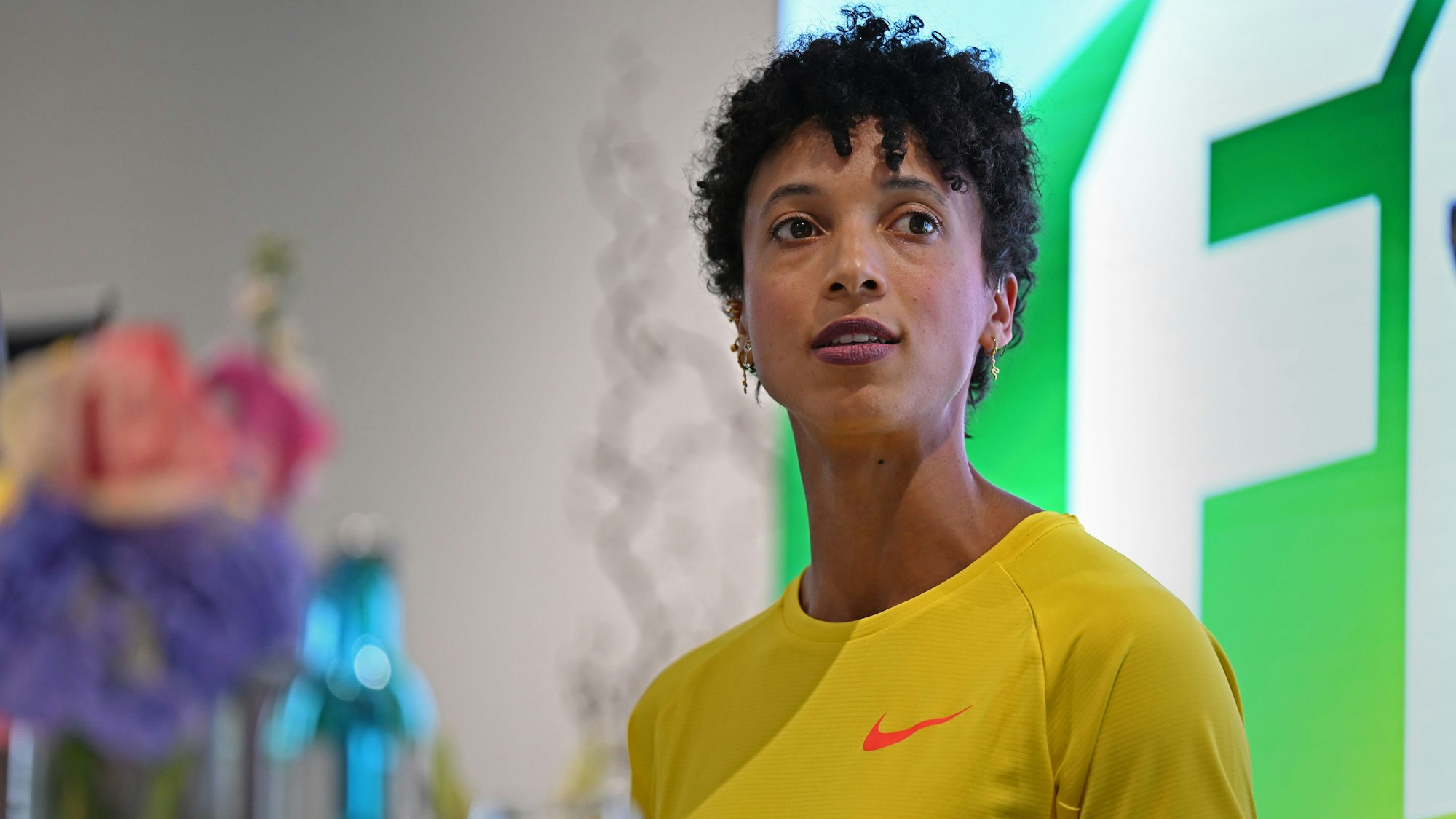 10.04.2025, Nordrhein-Westfalen, Köln: Die deutsche Leichtathletin und Weitspringerin Malaika Mihambo steht bei der Pressekonferenz der Fitnessmesse Fibo auf der Bühne und spricht zur Moderatorin. Die Fitnessstudio-Branche boomt, die Studios hatten noch nie so viele Mitglieder wie derzeit. Foto: Wolf von Dewitz/dpa +++ dpa-Bildfunk +++