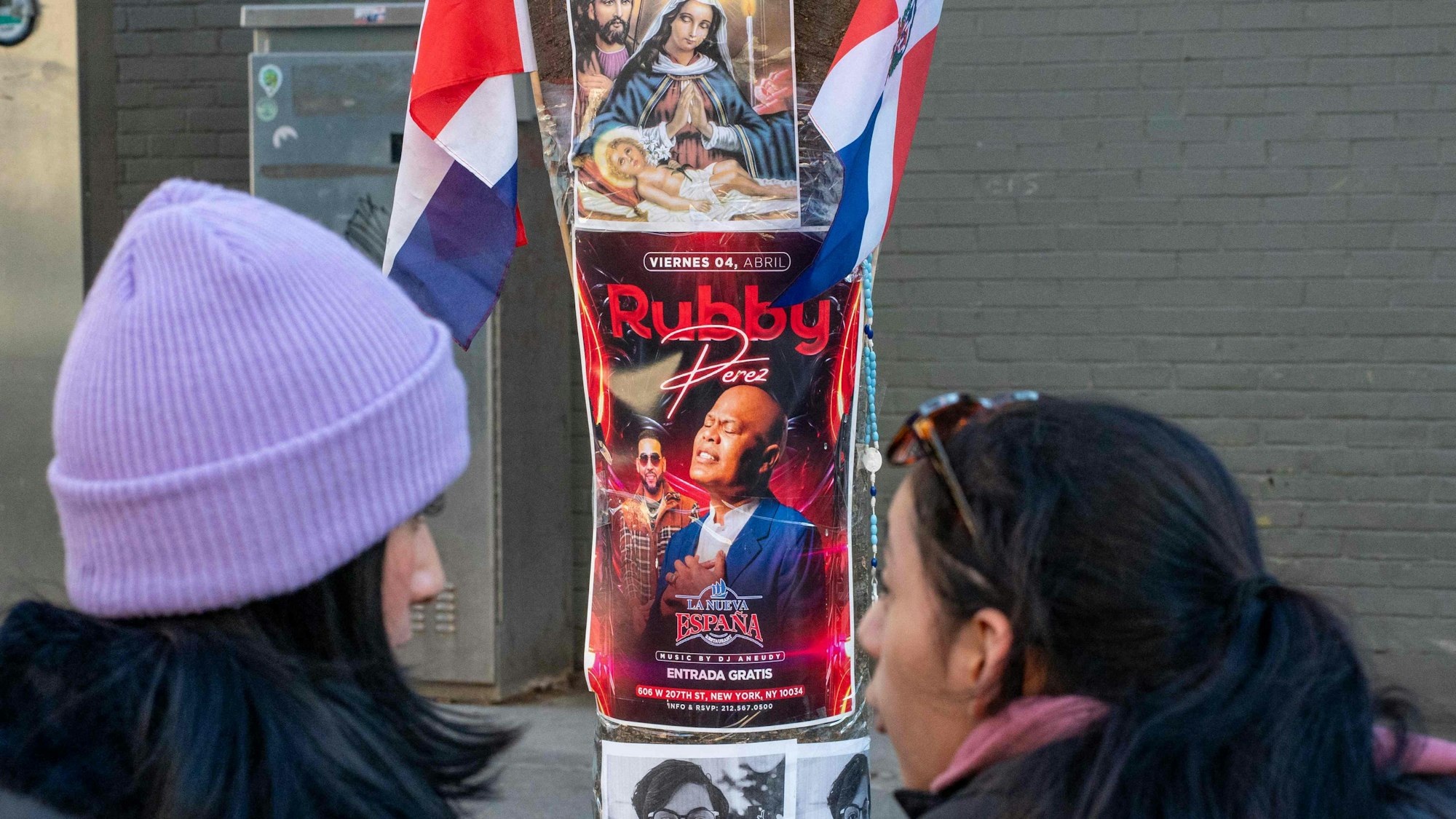 Zwei Frauen schauen auf das Konzertplakat von dem Musikstar Rubby Pérez.