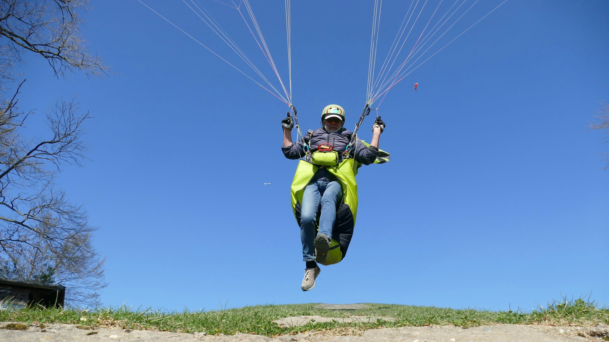 Eine Person stößt sich mit ein paar Schritten vom Boden ab, um mit dem Gleitschirm loszufliegen.