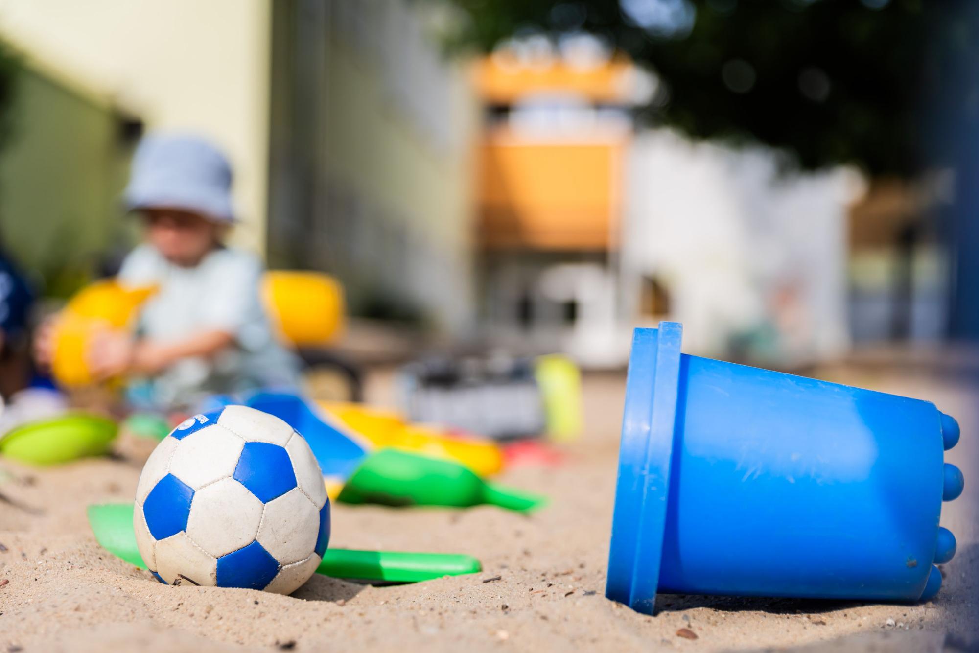 Ein Kind spielt im Sandkasten einer Kita.