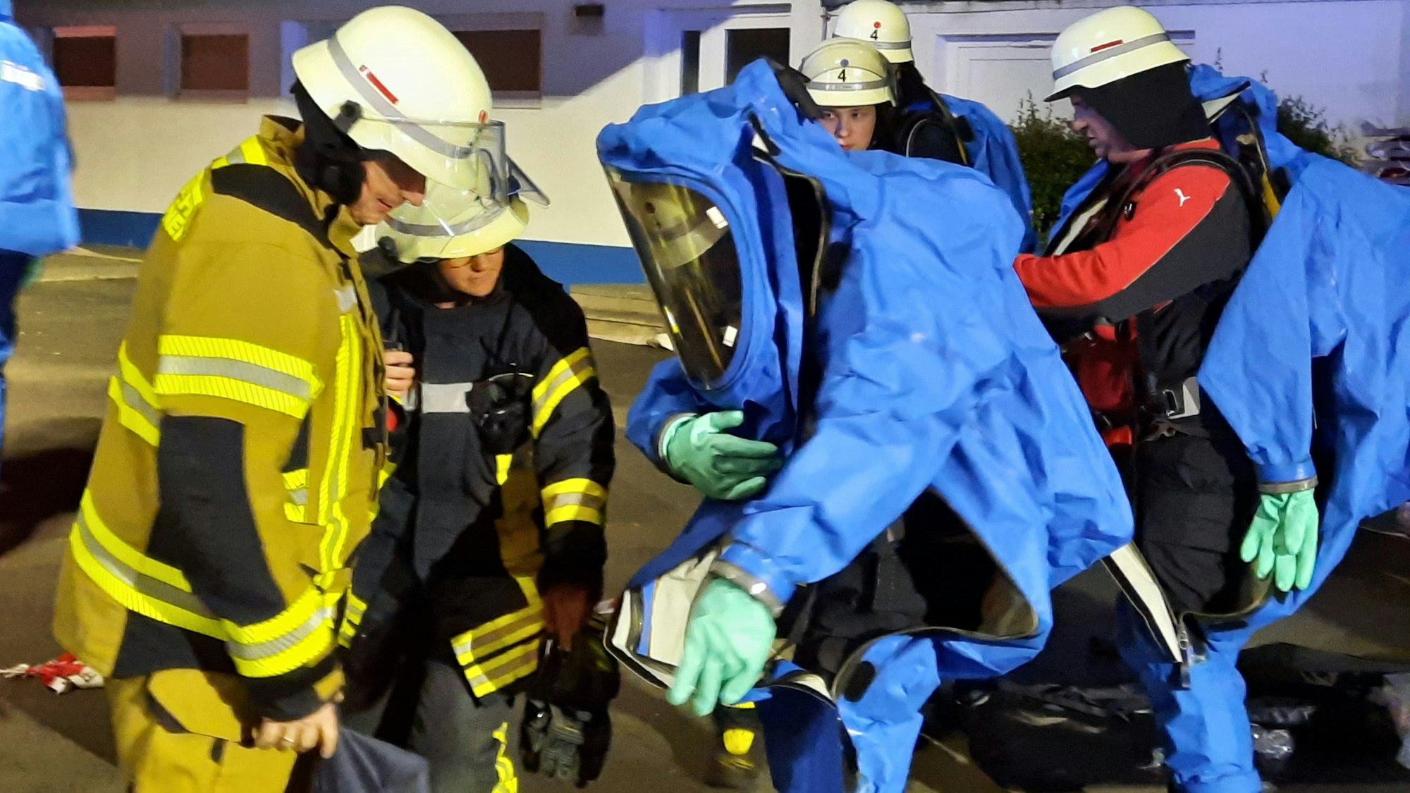 Feuerwehrleute ziehen spezielle Chemikalienschutzanzüge an und wollen dann den Raum des Freibads erkunden, in dem das Chlorgas ausgetreten ist.