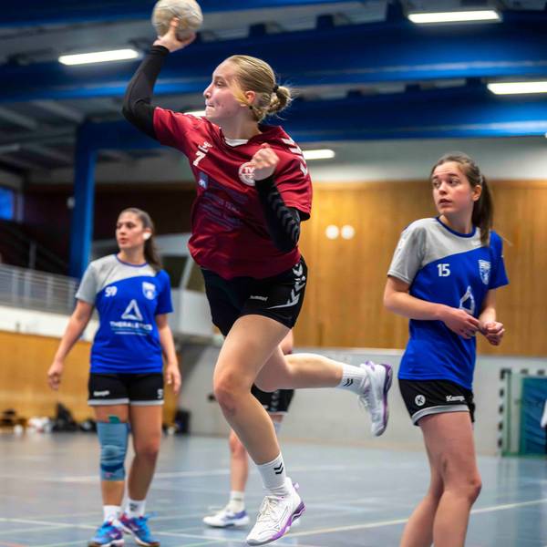 Eine junge Frau setzt mit einem Handball in der rechten Hand zum Wurf an.