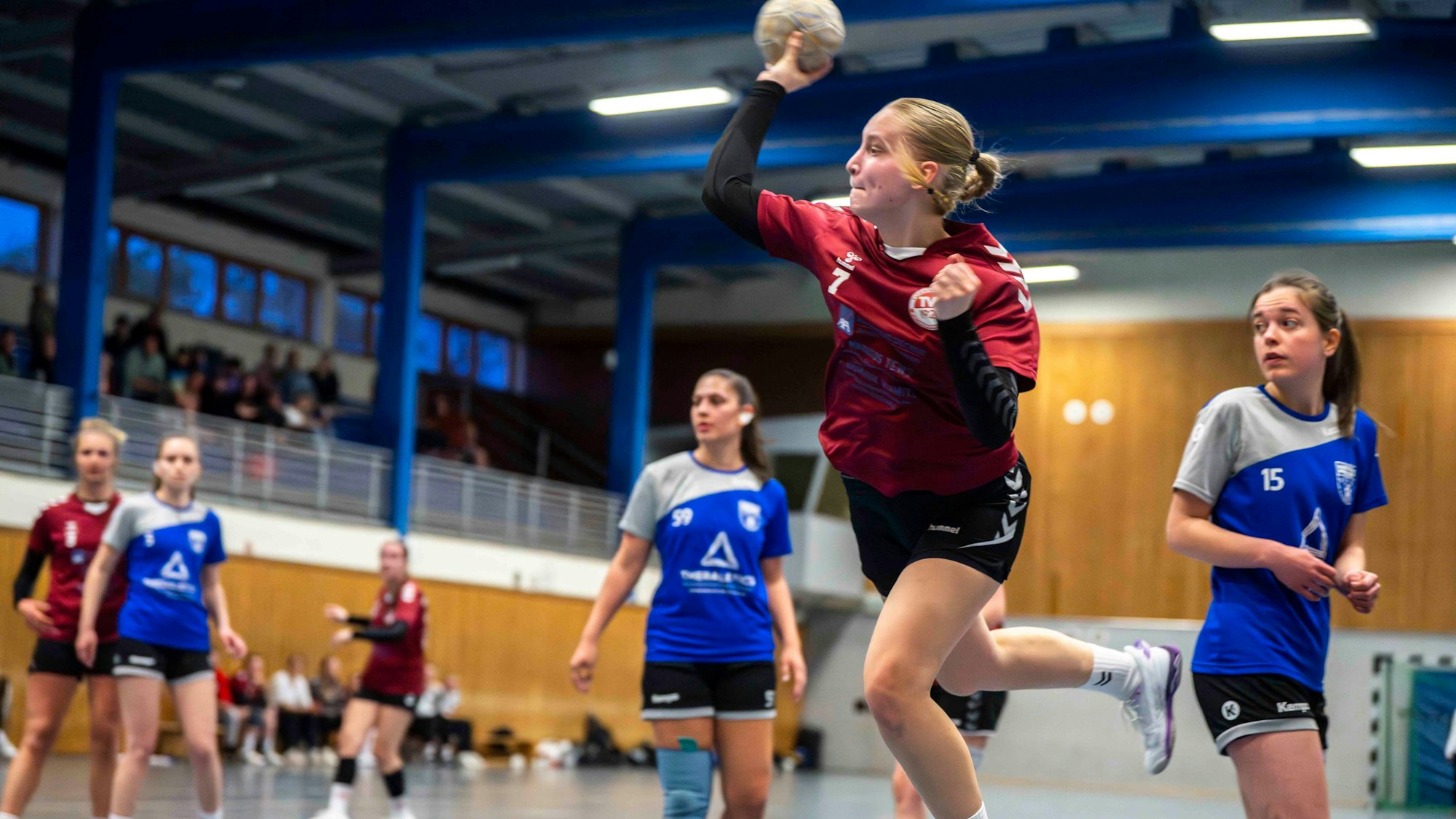 Eine junge Frau setzt mit einem Handball in der rechten Hand zum Wurf an.