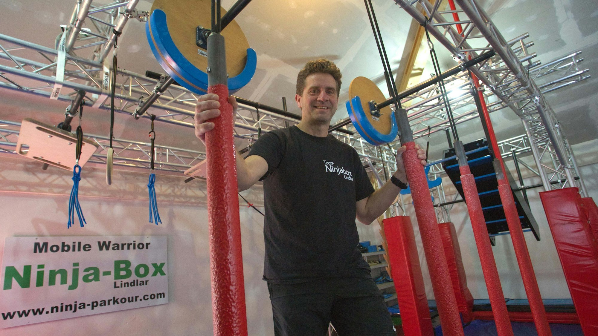 Blick auf einen Mann, der nach an der Decke befestigten Stangen fasst.