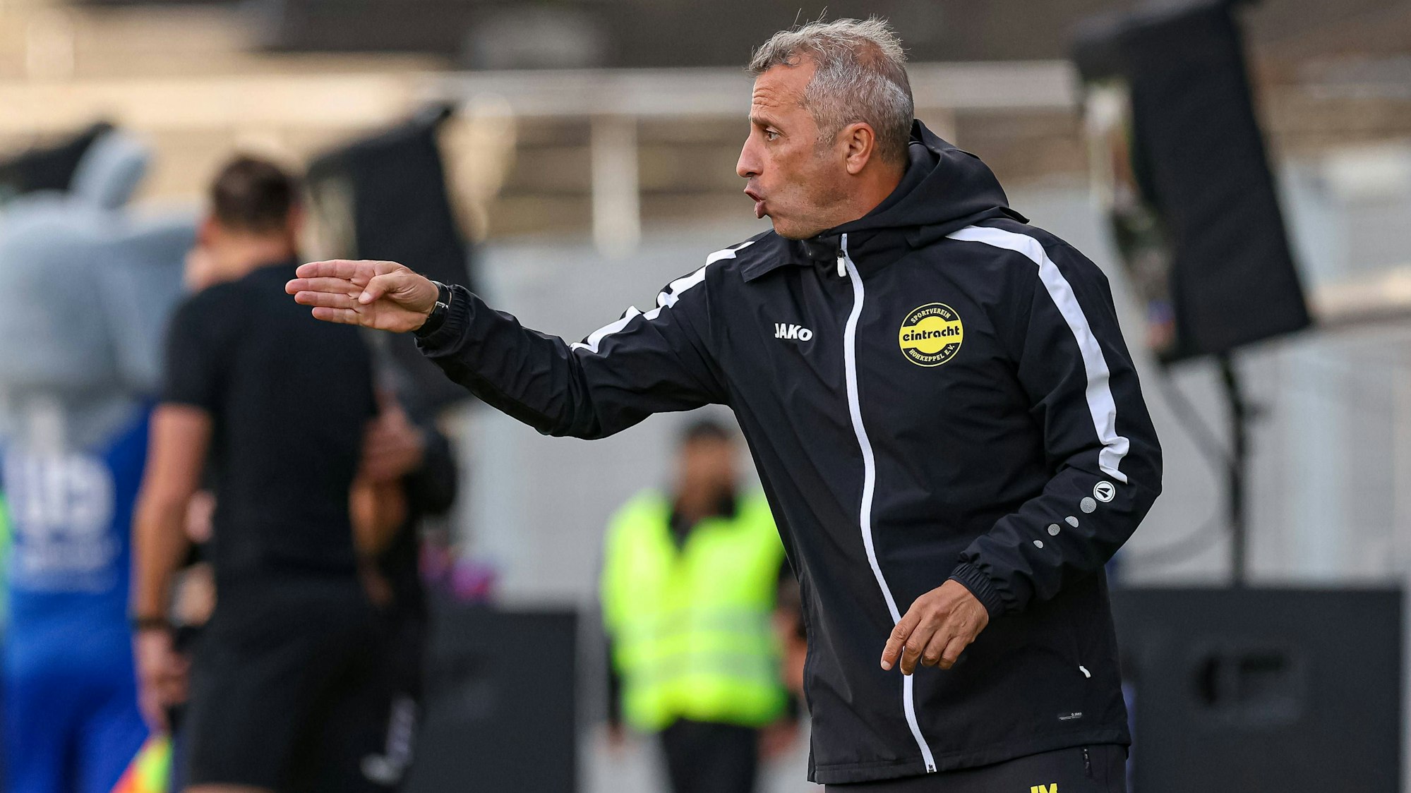 Ein Fußballtrainer gestikuliert am Spielfeldrand.