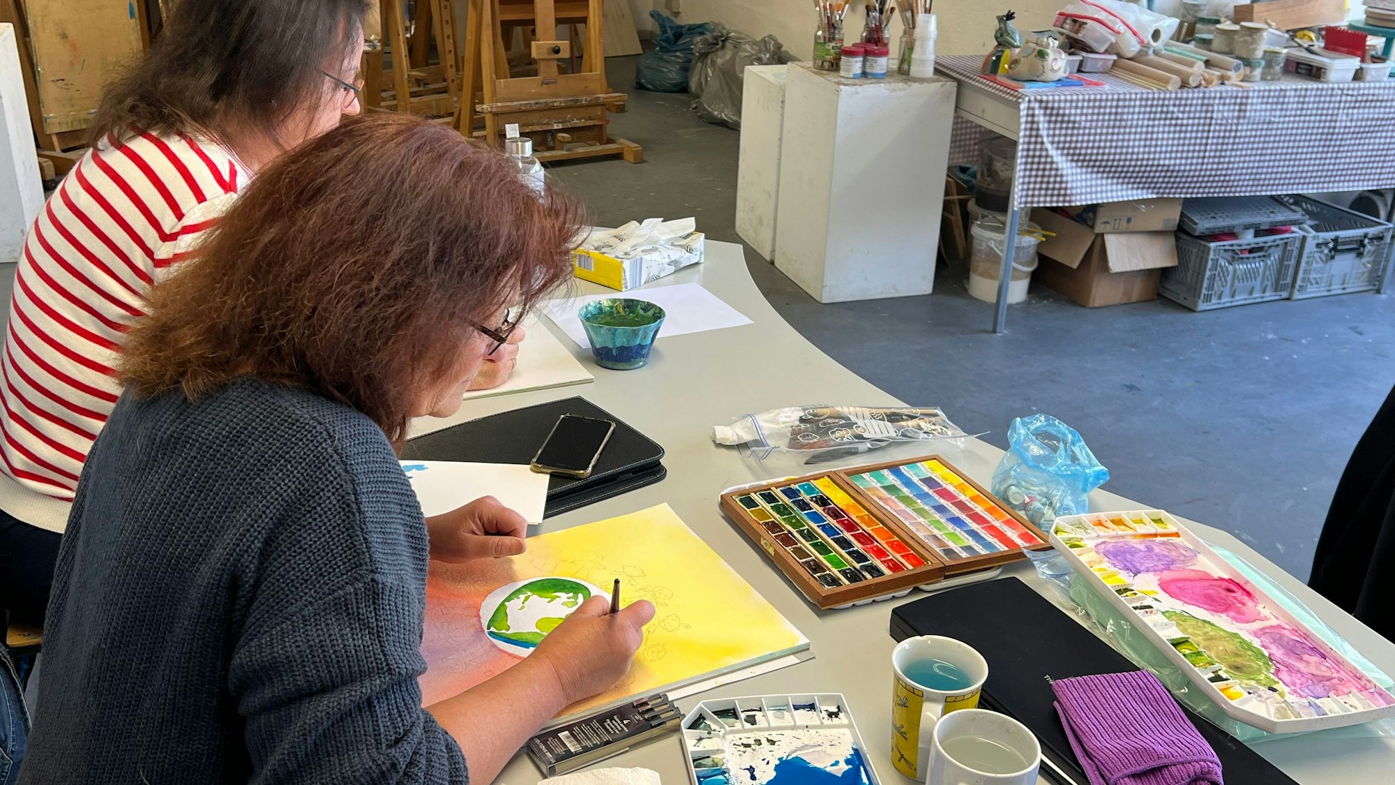 Frauen malen in einem Kursraum.