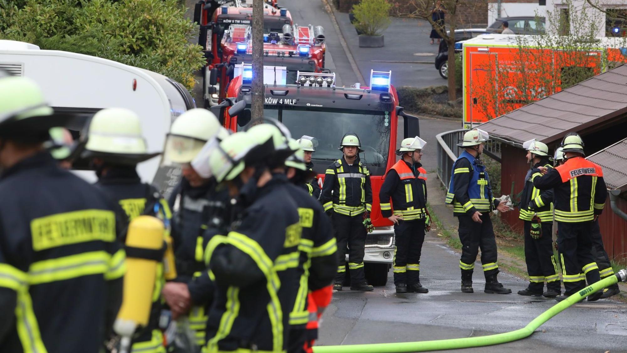 Feuerwehrkräfte stehen vor einem Haus in Oberpleis. Drei Einsatzwagen stehen mit Blaulicht an der Straße.