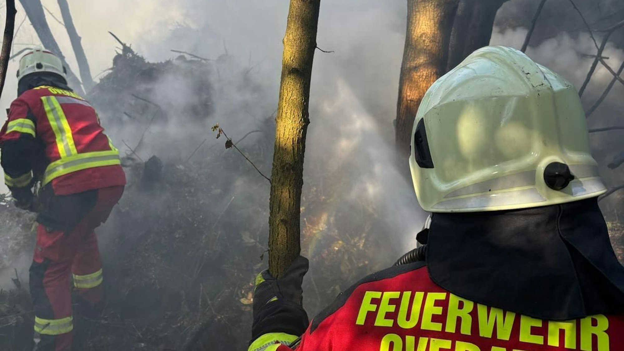 Zwei Feuerwehrmänner löschen einen Brand.