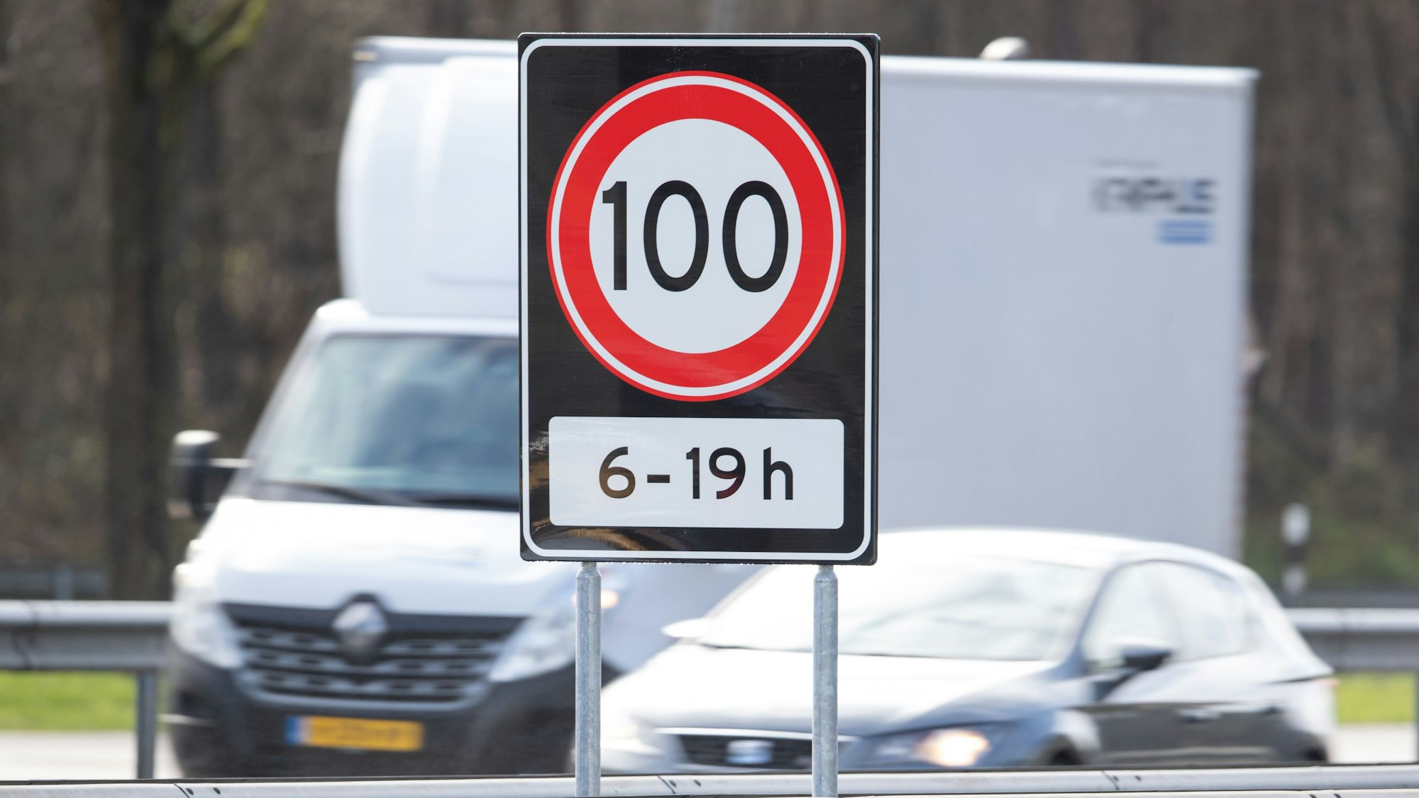 Tempo 100 von 6 bis 19 Uhr steht auf einem Verkehrsschild auf einer Autobahn an der Grenze zwischen den Niederlanden und Deutschland. Nach Norwegen und Zypern führen auch die Niederlande Tempo 100 als Höchstgeschwindigkeit auf allen ihren Autobahnen ein.