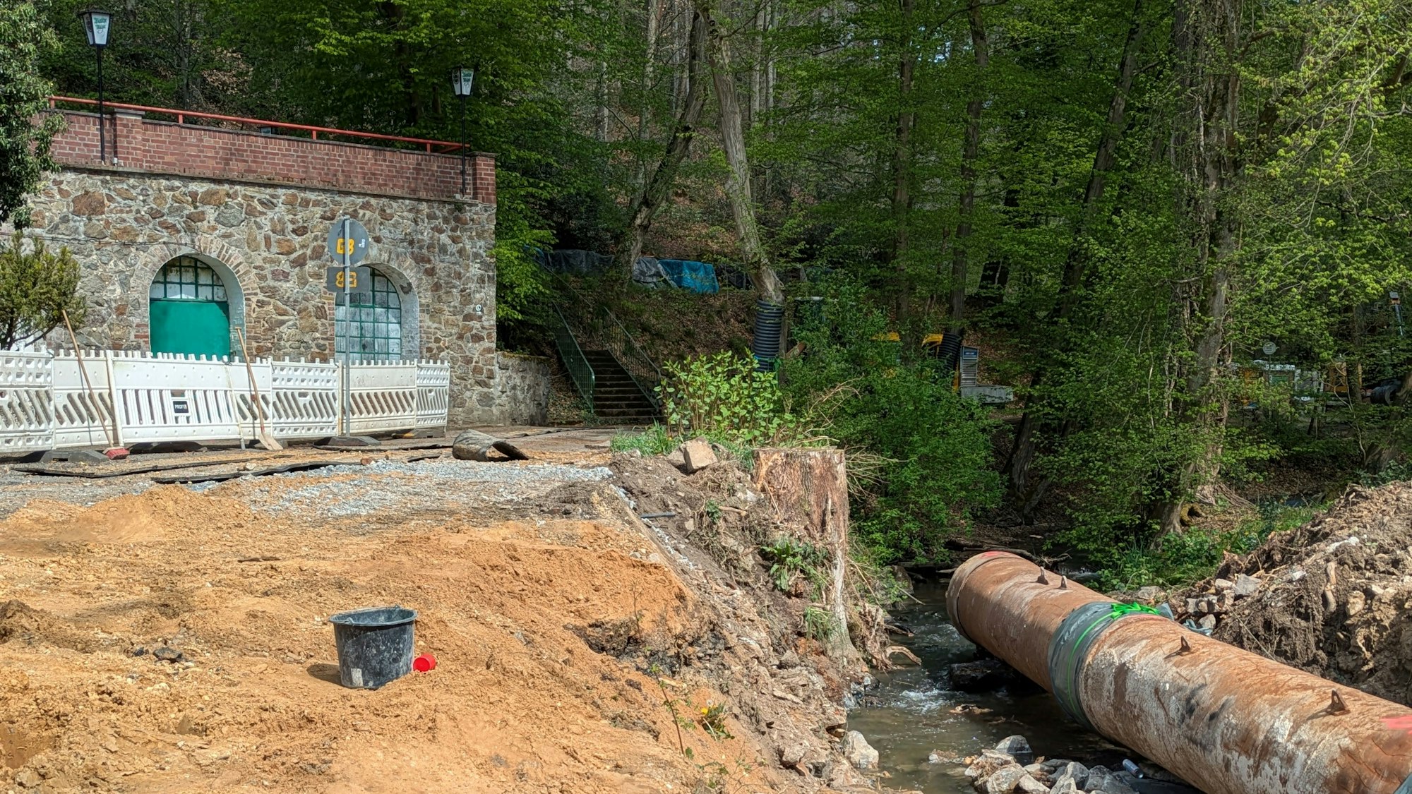 Ein Stahlrohr liegt für die Bauarbeiten an der Brücke bereits im Bachbett, links die Terrasse des ehemaligen Ausflugscafés Wietsche Mühle.